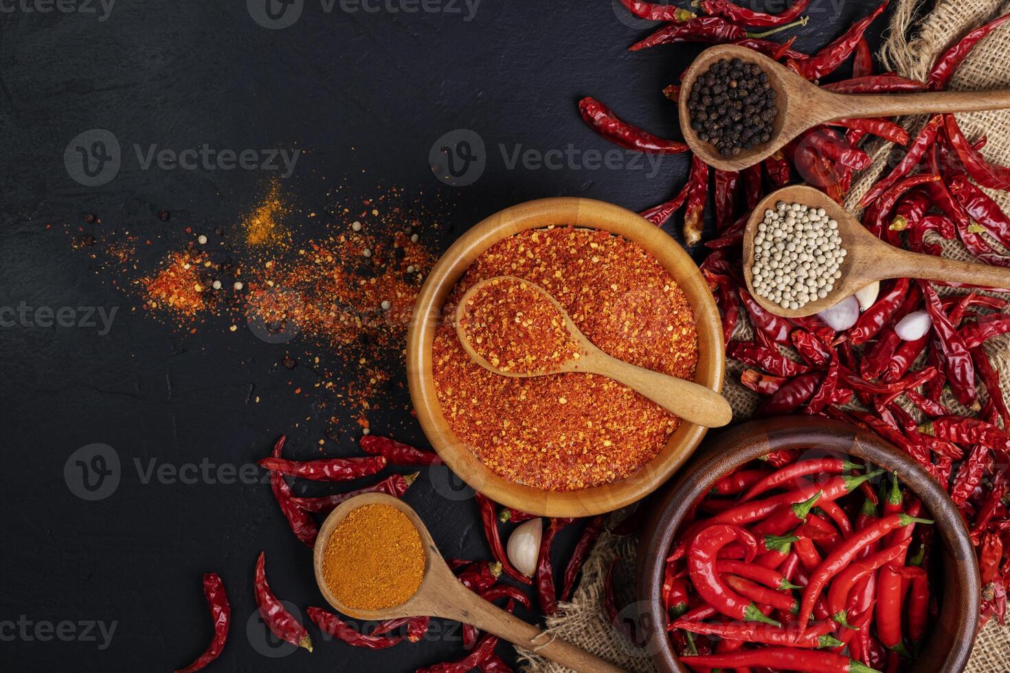 Dried chilies with chili powder, pepper, and red paprika in a wooden bowl Spicy seasoning Healthy food, top view photo