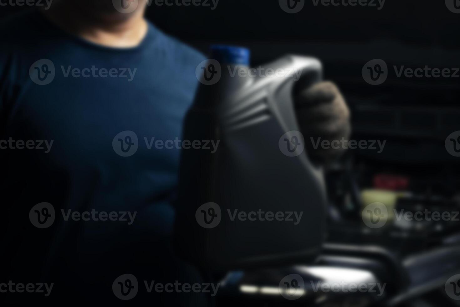 Blurred background of a mechanic holding a bottle of lubricant Engine background, oil change shop, engine service industry. photo