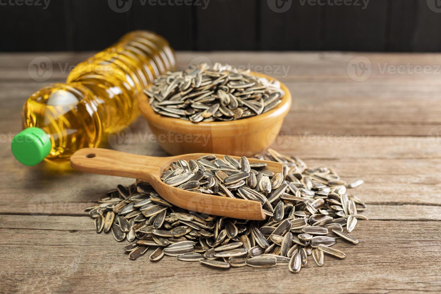 Sunflower seeds with a bottle of sunflower seed oil On a simple, traditional wooden floor Organic food and environment concept Healthy food and fat photo