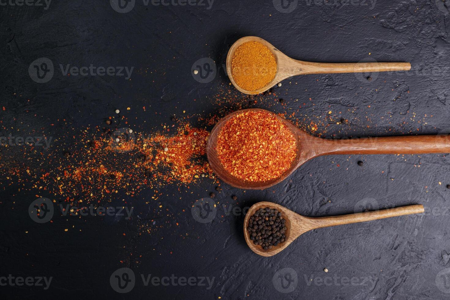 Dried chilies with chili powder, pepper, red paprika in a wooden spoon Spicy seasoning Healthy food, top view photo