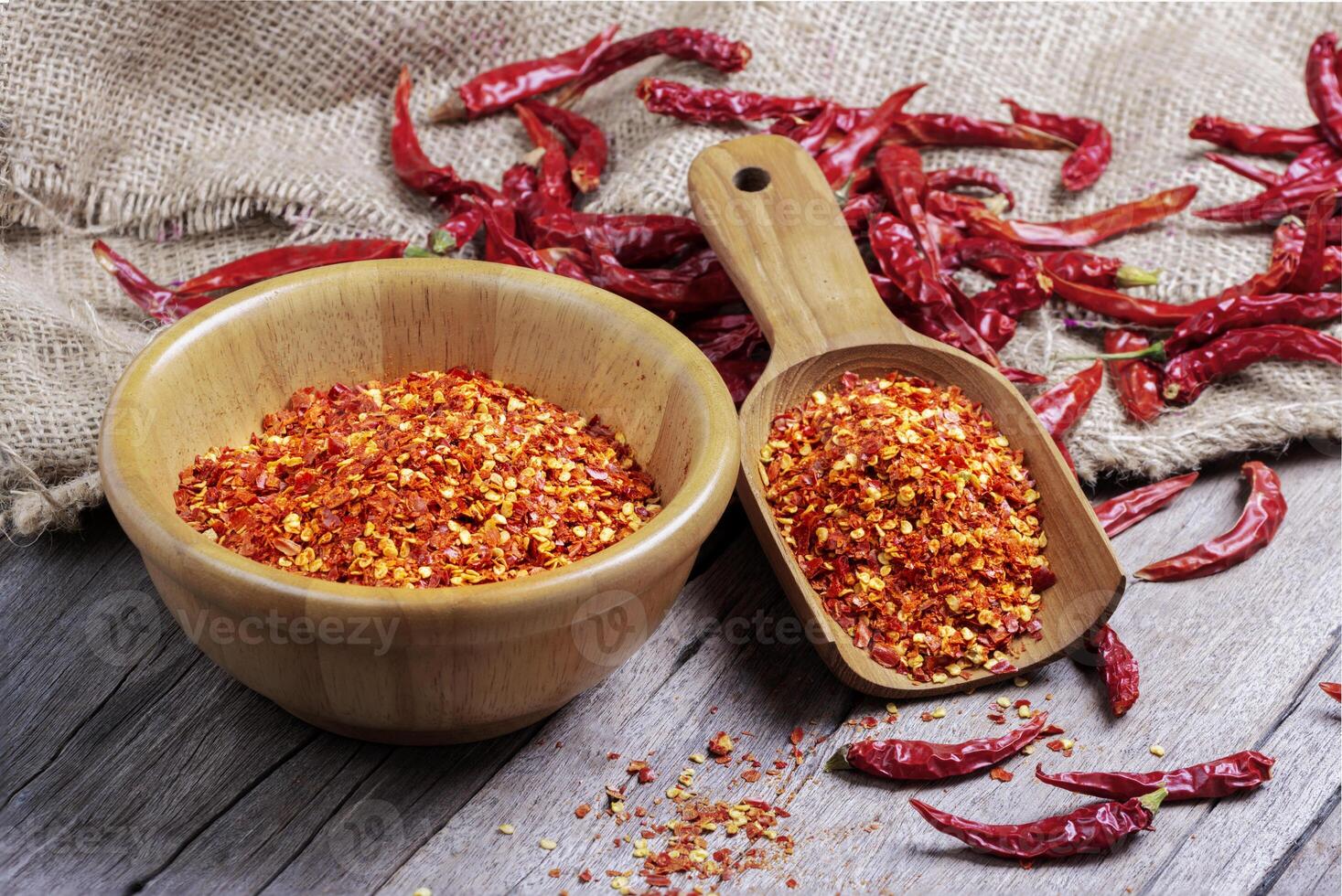 Dried chilies with chili powder, pepper, and red paprika in a wooden bowl Spicy seasoning Healthy food, top view photo