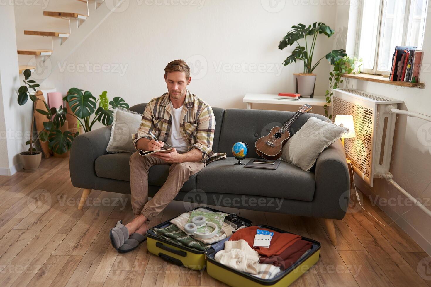 Portrait of man, tourist makes plans for his next vacation, writing a list of things to take with him, making a check-list photo