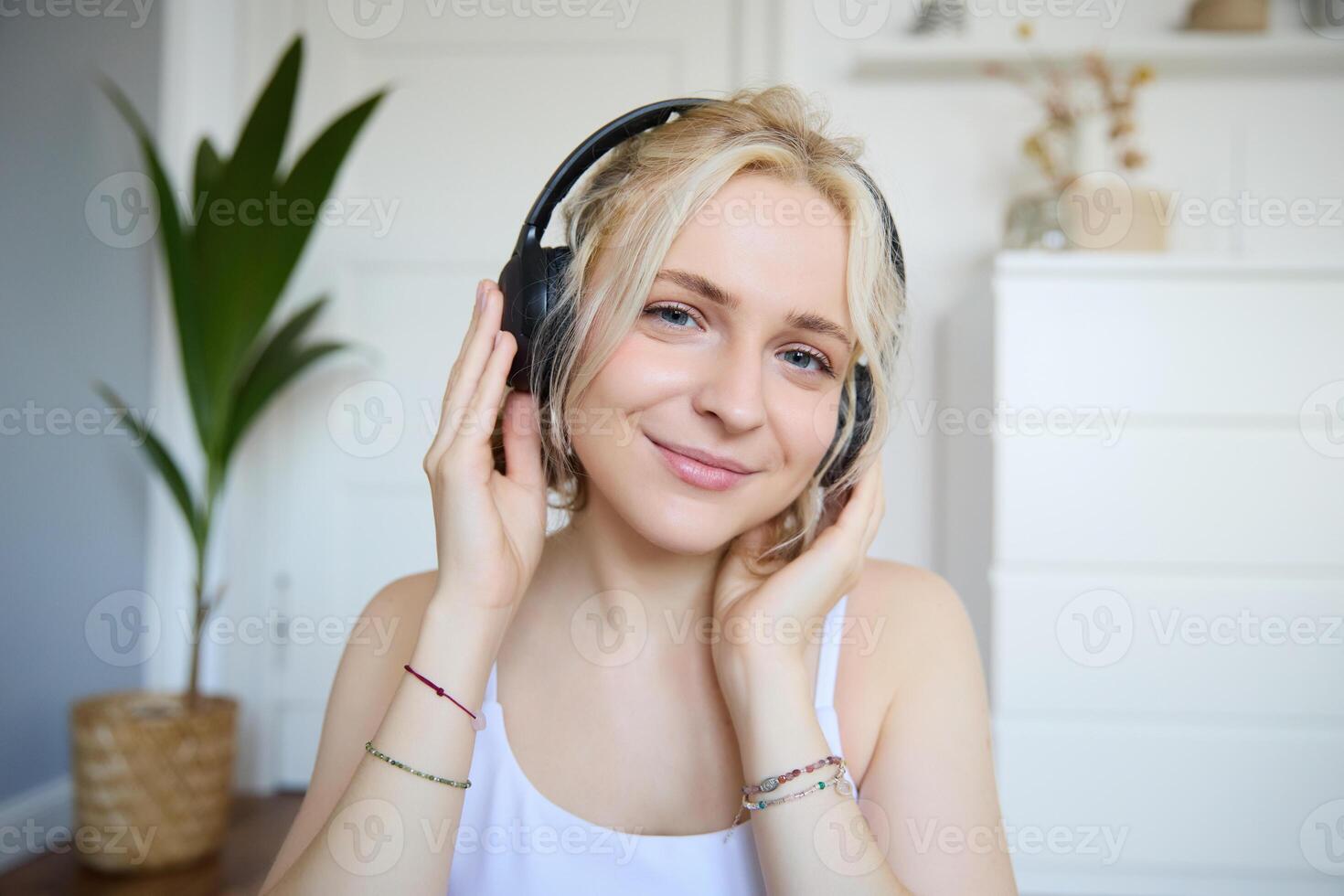 Concept of people and lifestyle, Close up of beautiful blond woman in wireless headphones, listens to music, enjoys good quality sound in new earphones photo