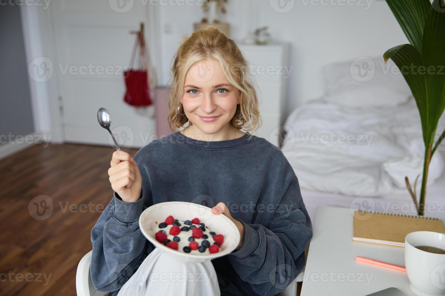 Portrait of young vlogger, content creator, showing her homemade breakfast on camera, eating dessert, smiling and looking happy photo