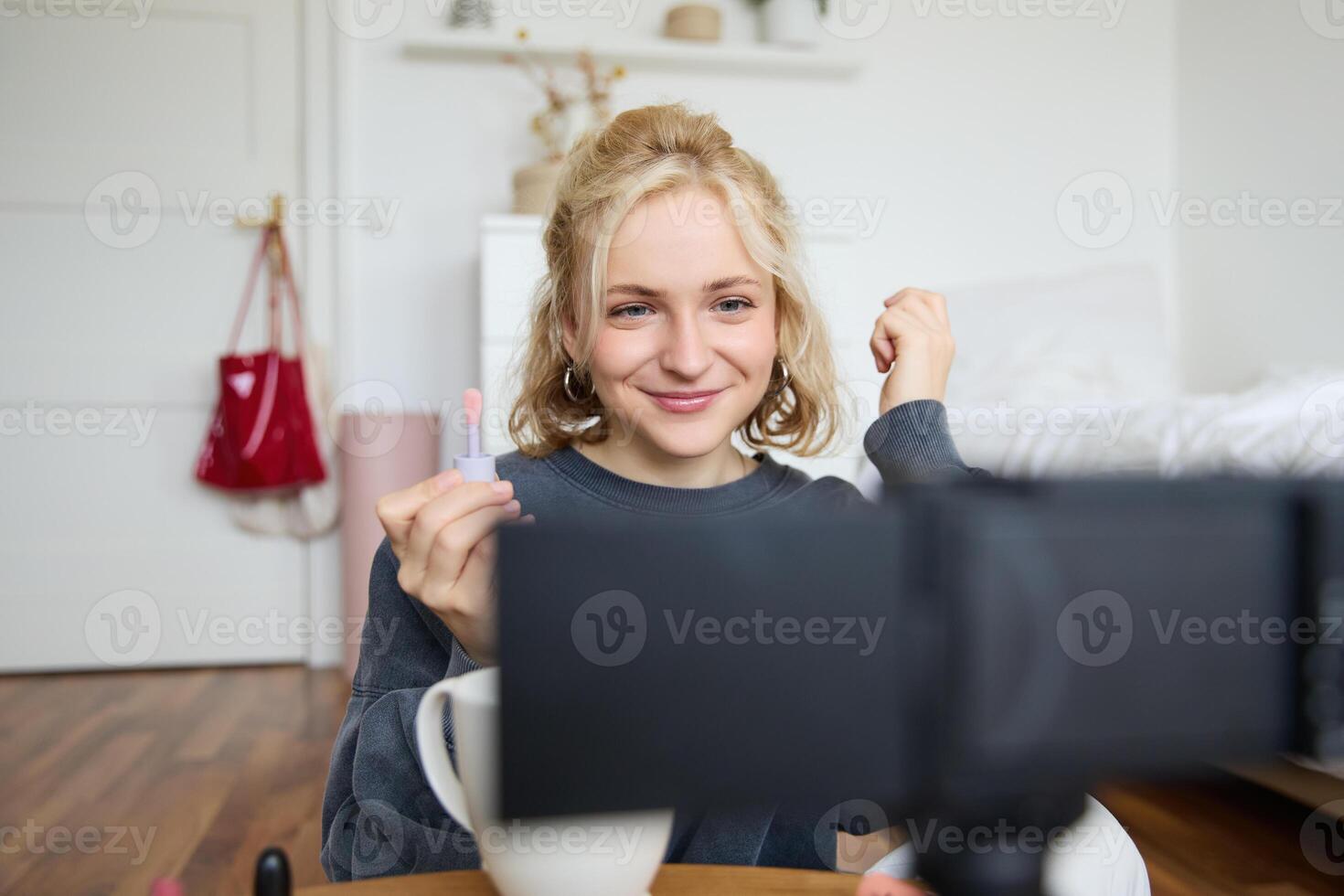 Image of happy, beautiful young social media influencer, female vlogger records a on digital camera, tutorial on how to put makeup, getting ready for going out, talking to followers photo