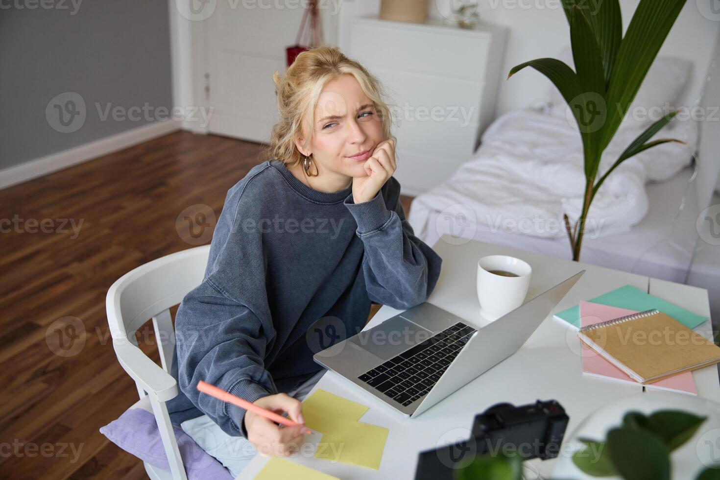 retrato de joven pensativo chica, estudiando, haciendo notas, escritura abajo alguna cosa en computadora portátil, haciendo deberes en su habitación, sentado en frente de computadora portátil, ceñudo mientras pensando foto