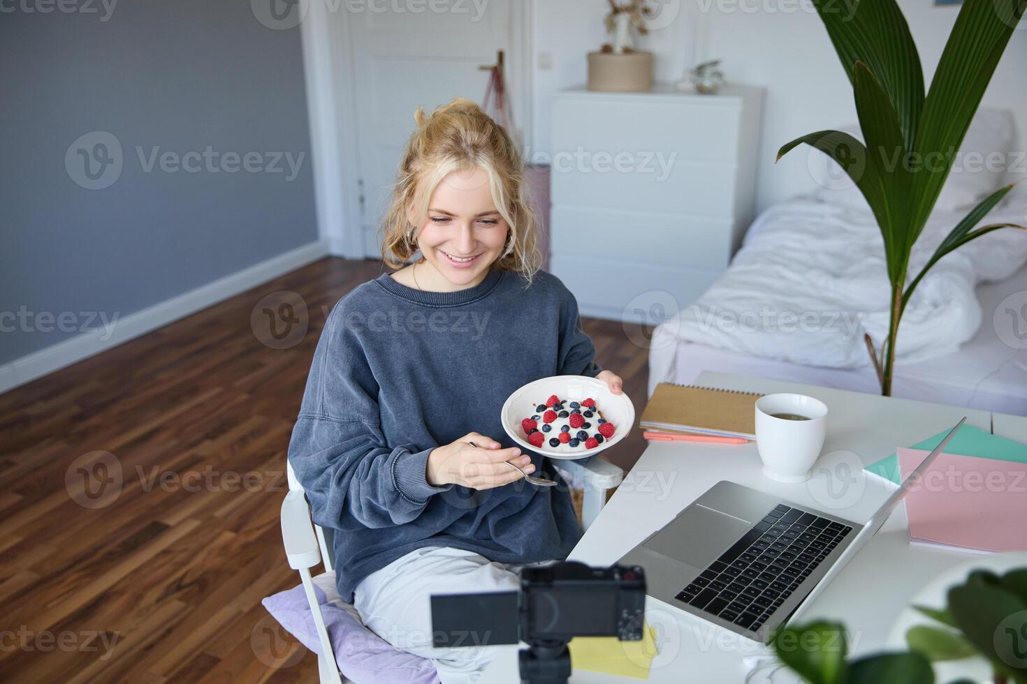 retrato de joven mujer vloguero, grabación sí misma mientras comiendo hecho en casa sano desayuno, creando vlog contenido para seguidores foto