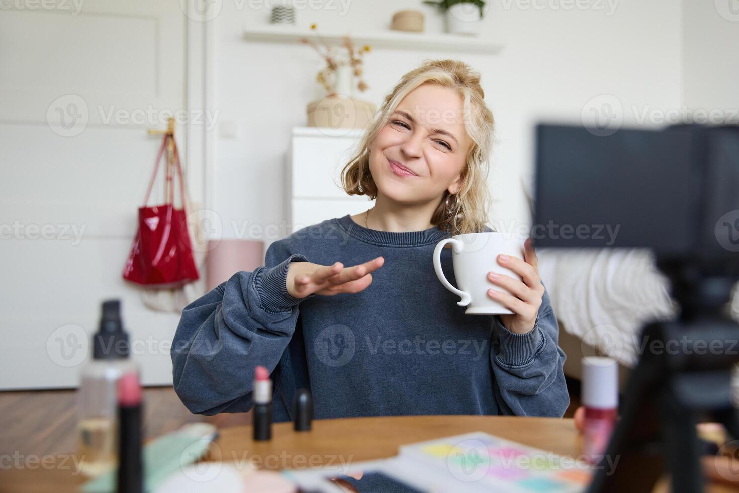 Portrait of stylish lifestyle blogger, woman talking in front of camera, records vlog about her day in life, drinks tea and speaks to audience photo