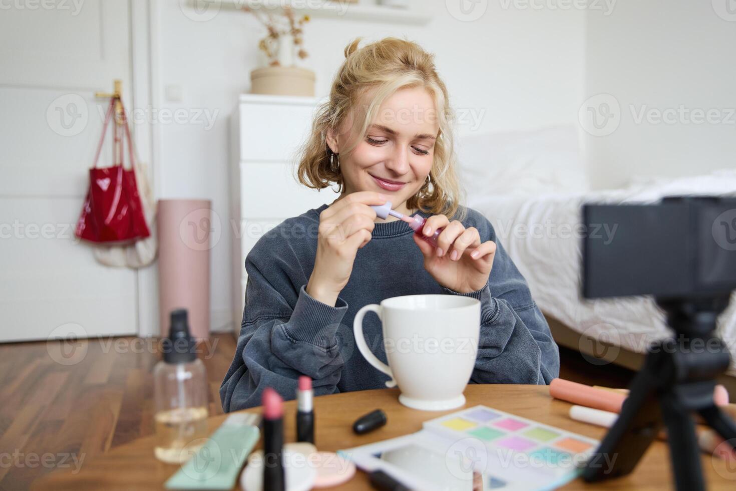 Image of happy, beautiful young social media influencer, female vlogger records a on digital camera, tutorial on how to put makeup, getting ready for going out, talking to followers photo