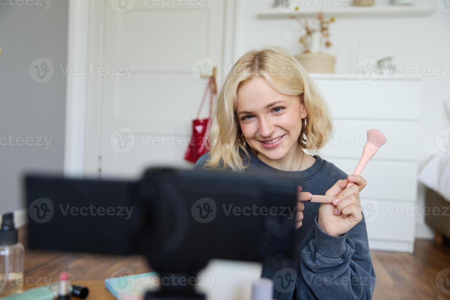 Portrait of beauty blogger, woman records on camera in her room, shows makeup beauty products, talks about cosmetics in vlog, makes lifestyle content for followers on social media photo