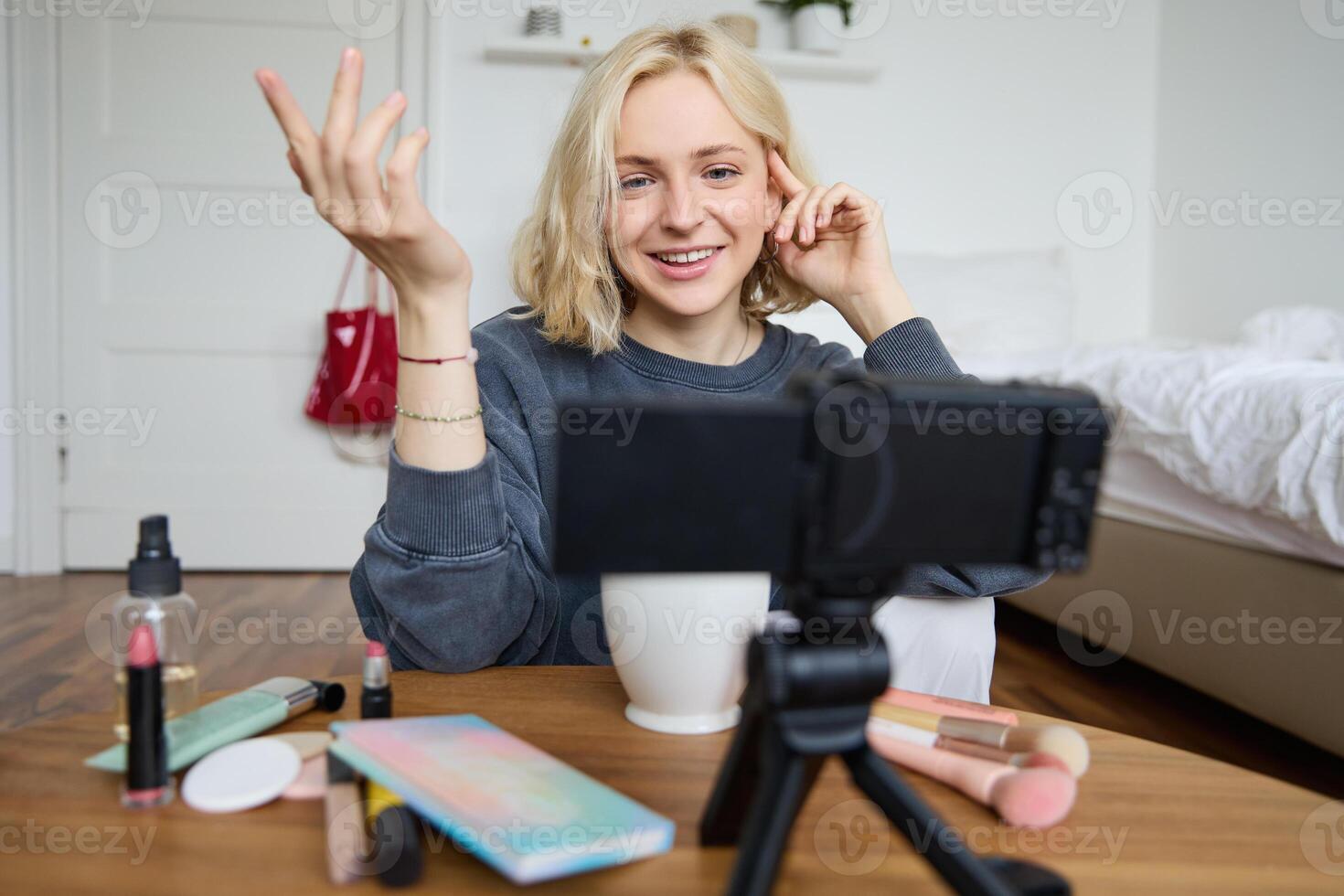 Portrait of young teenage girl in her room, recording a vlog, daily lifestyle for social media, internet influencer advertising product online, talking to the camera, sitting on the floor photo