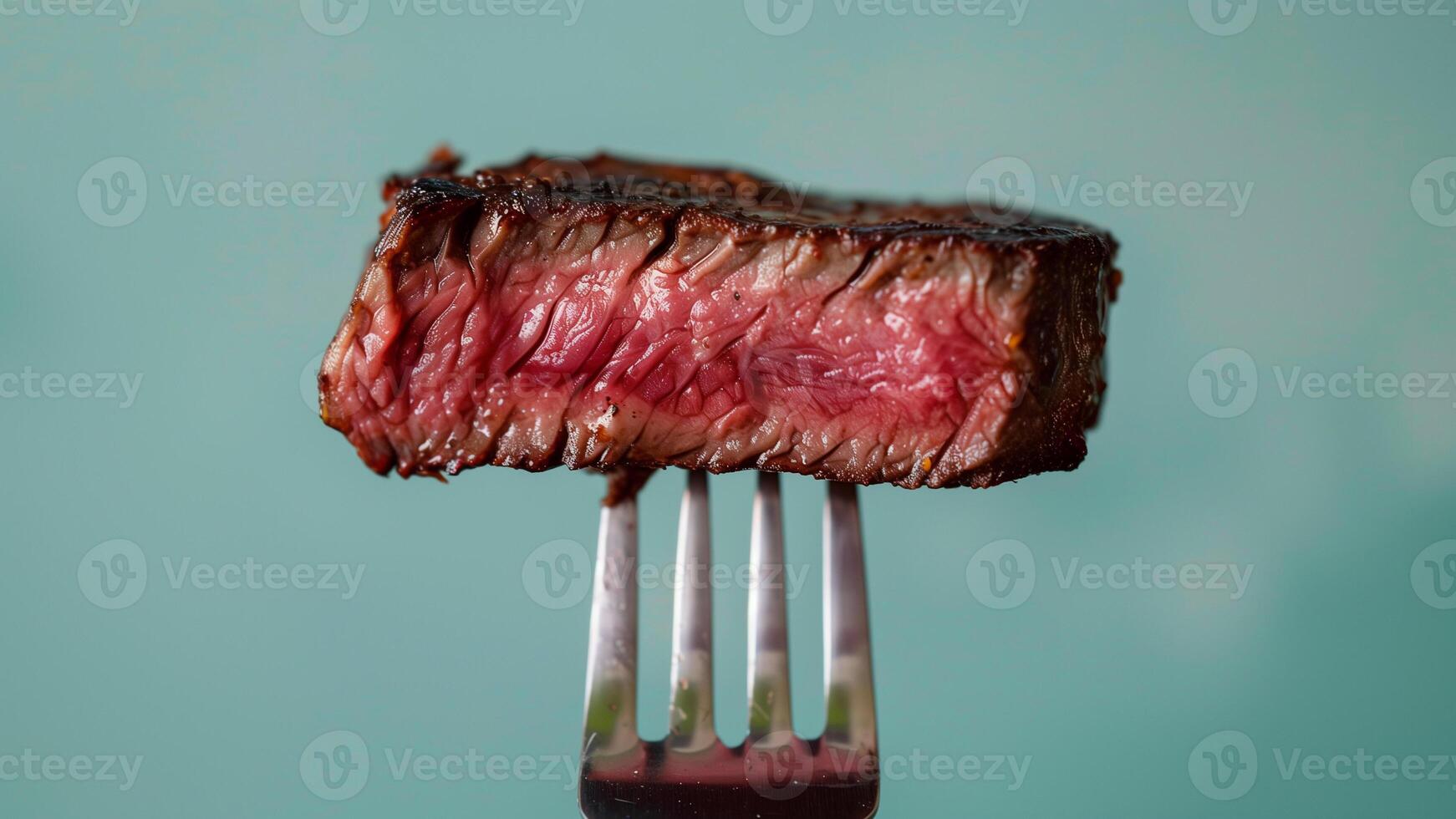 Grilled beef steak on a fork on a green background closeup photo