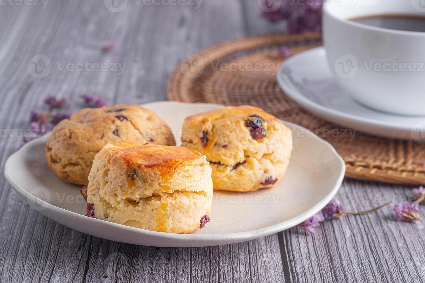 Close-up of traditional British scones and cookies on a plate with a teacup and flower blurred background. Space for text photo