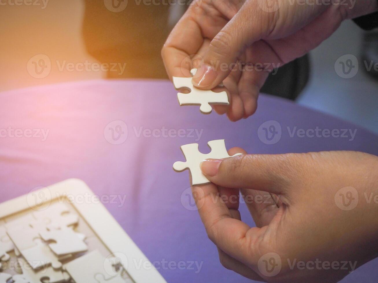 Close-up of hands woman's holding connecting jigsaw puzzle with sunlight effect. Space for text photo