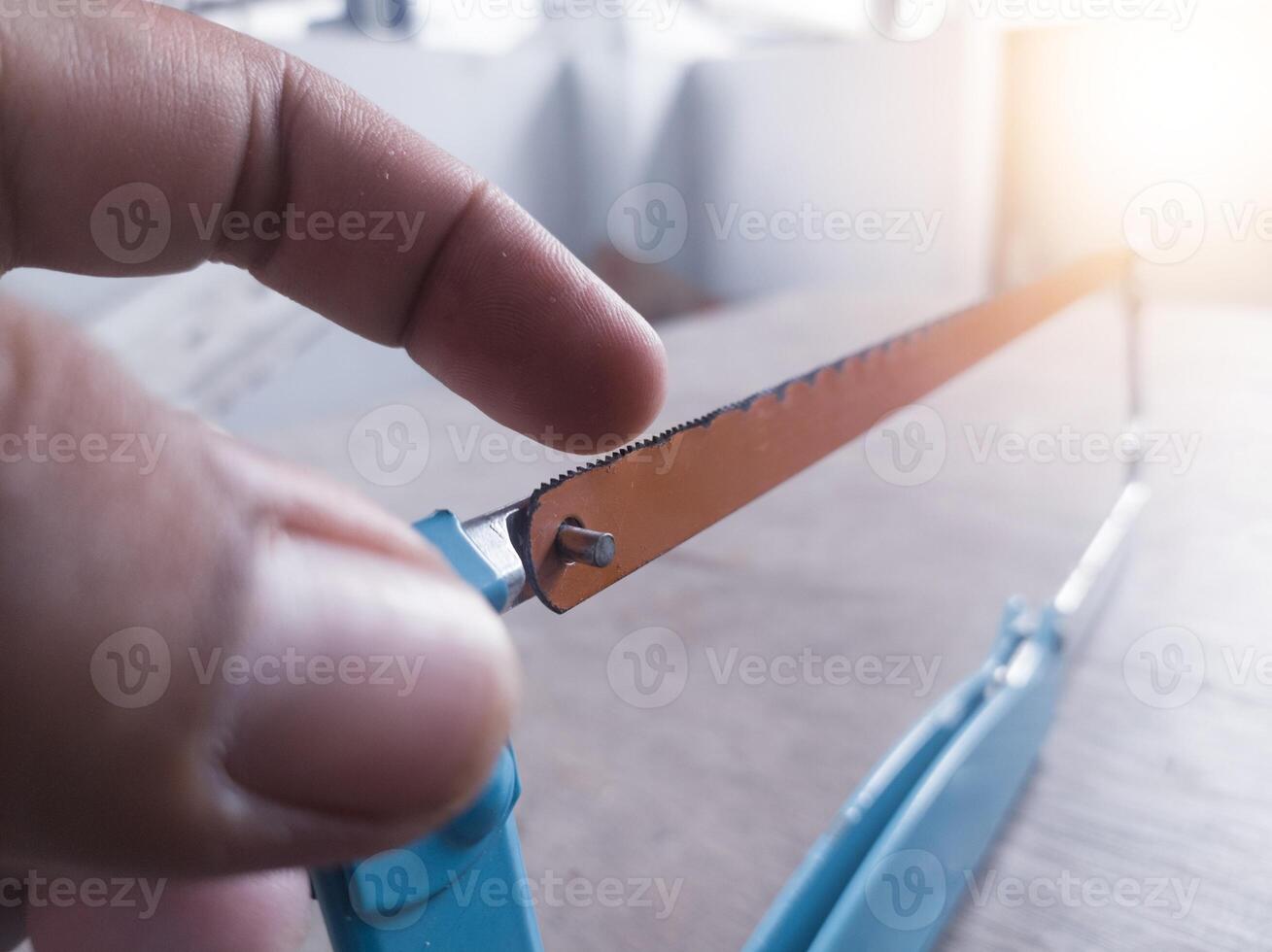 Checking sharpness and showing the correct direction of the hacksaw teeth. photo