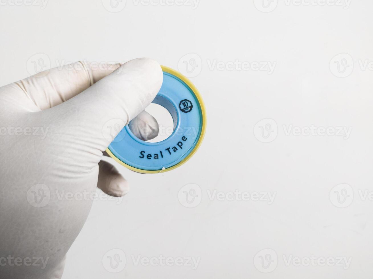 Man's hand with gloves holds a seal tape isolated on white background. Plumbing equipment concept. photo