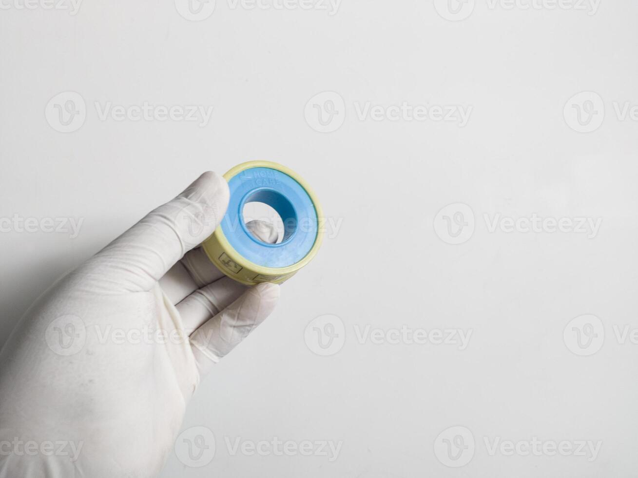 Man's hand with gloves holds a seal tape isolated on white background. Plumbing equipment concept. photo