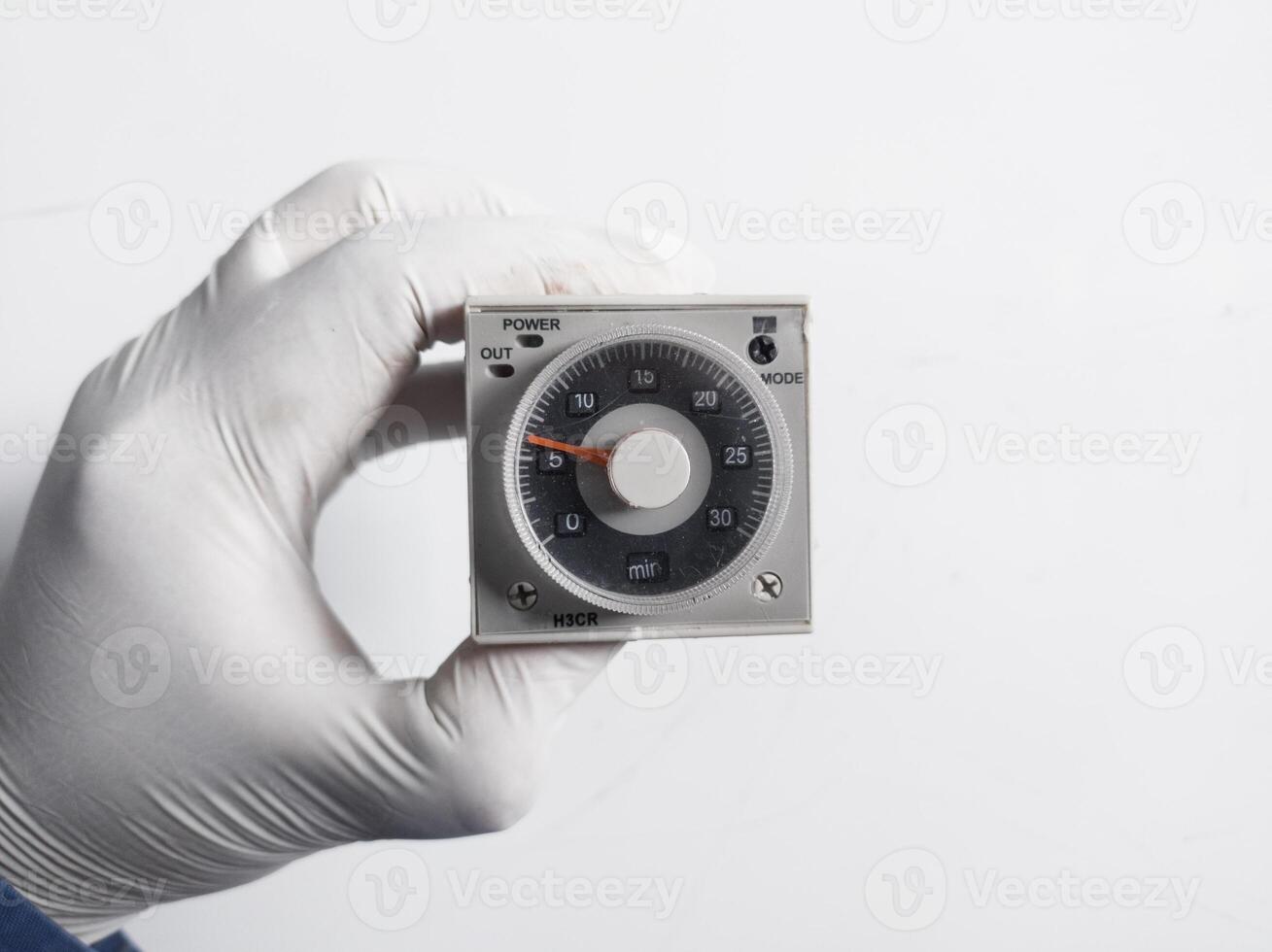 Man's hand with gloves holds Electric Timer H3CR isolated on white background. Electrical Equipment concept. photo