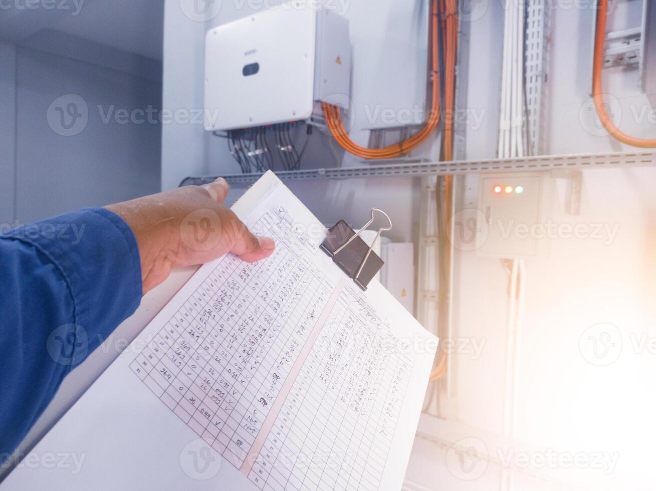 An inspector is pointing to the solar panel inverter module, having the concept of checking and monitoring the solar panel inverter. comissioning concept. photo