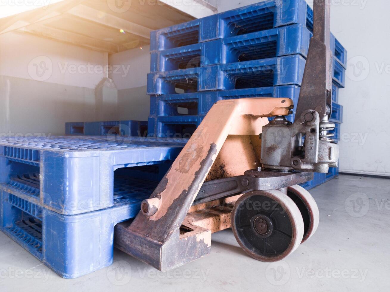 Hand pallet jack and some blue pallet on the distribution warehouse area. photo