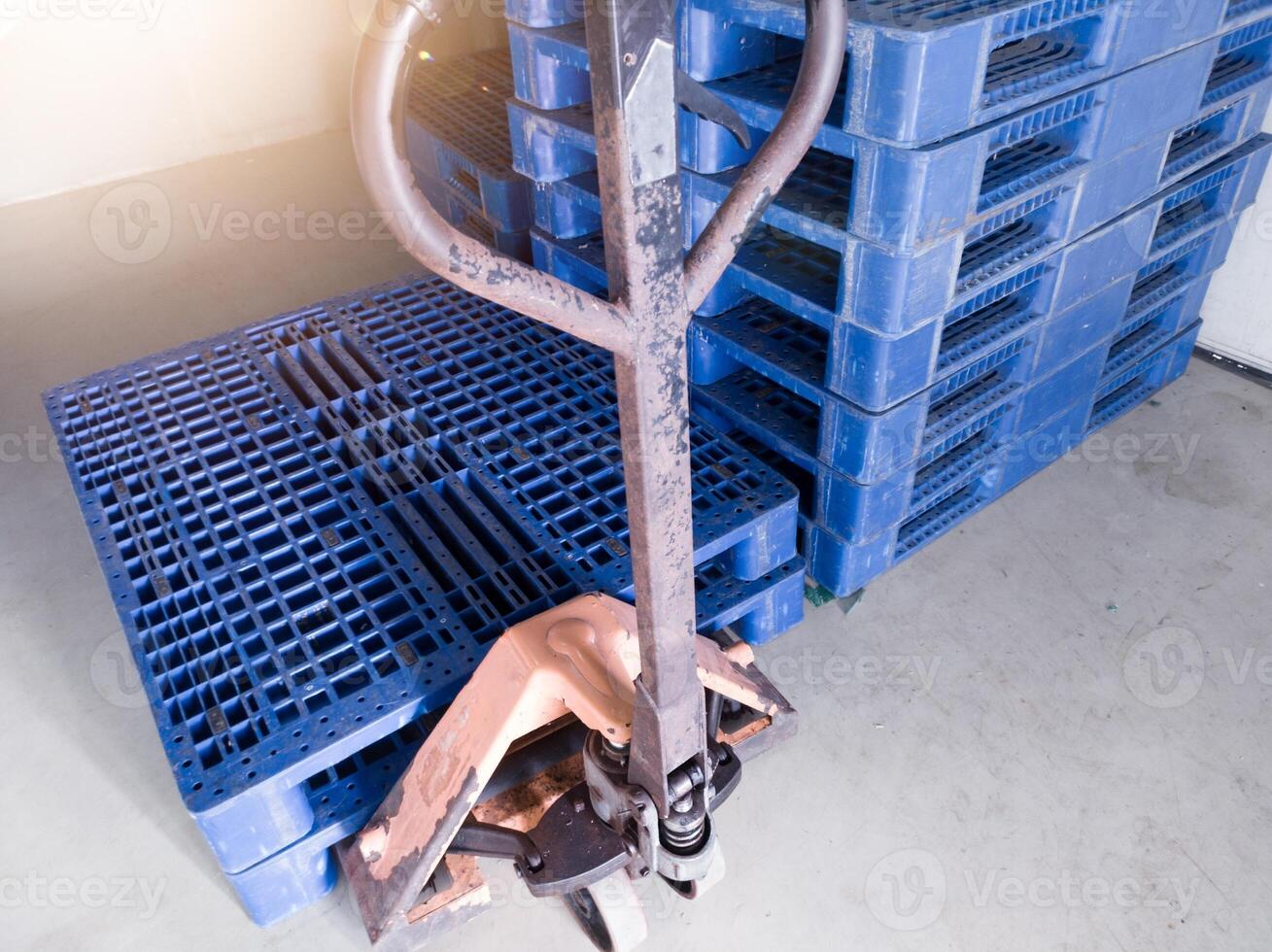 Hand pallet jack and some blue pallet on the distribution warehouse area. photo