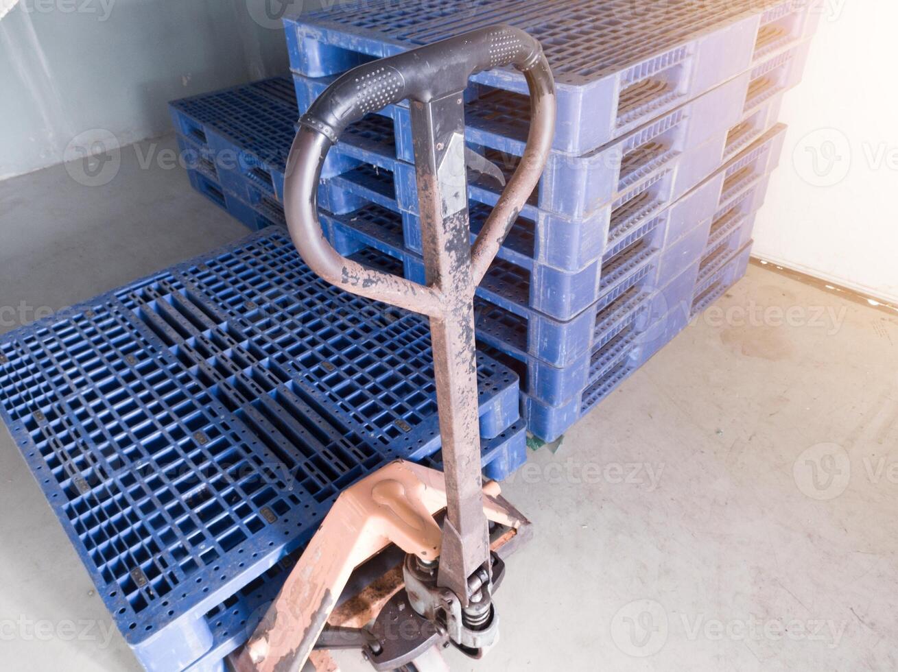 Hand pallet jack and some blue pallet on the distribution warehouse area. photo