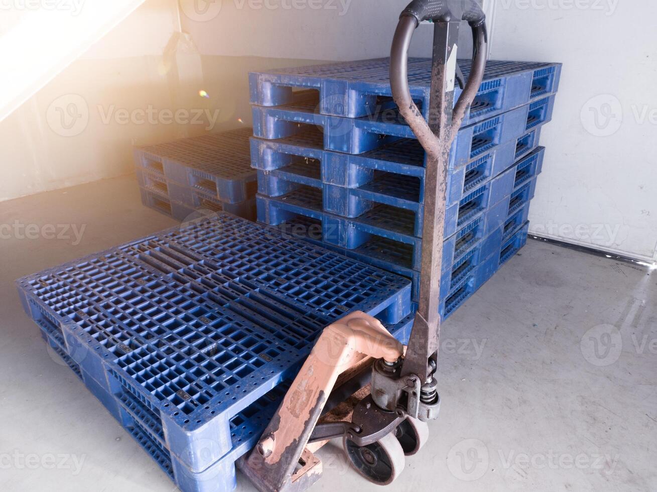 Hand pallet jack and some blue pallet on the distribution warehouse area. photo