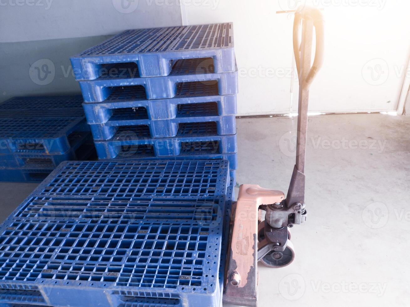 Hand pallet jack and some blue pallet on the distribution warehouse area. photo