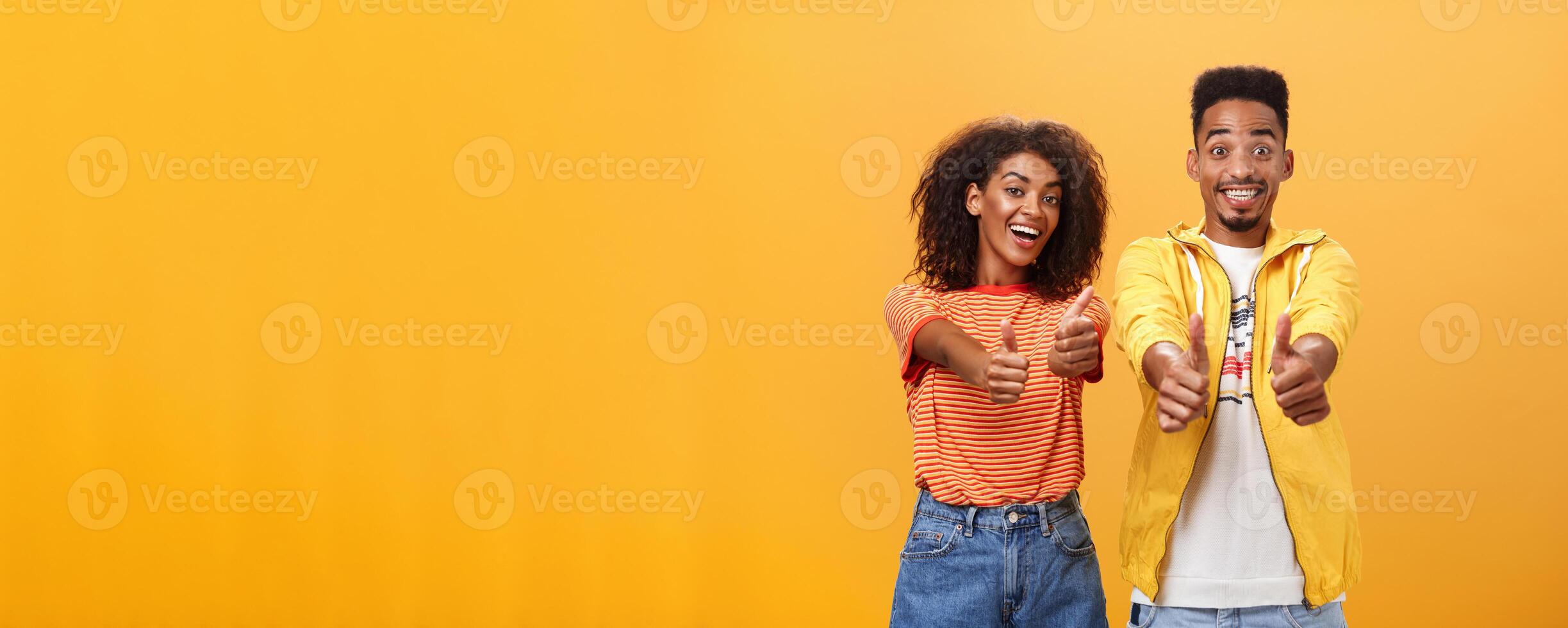 dos amigos me gusta Perfecto y increíble plan. retrato de alegre de apariencia amistosa optimista africano americano hembra y masculino demostración pulgares arriba en aprobación y acuerdo gesto sonriente en general foto