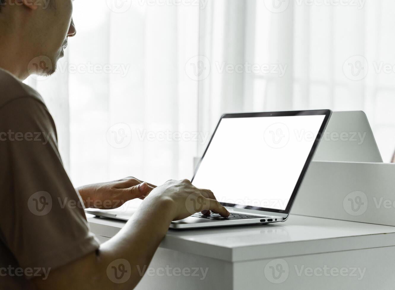 Man's hands using laptop with blank screen on white table at home or office. photo