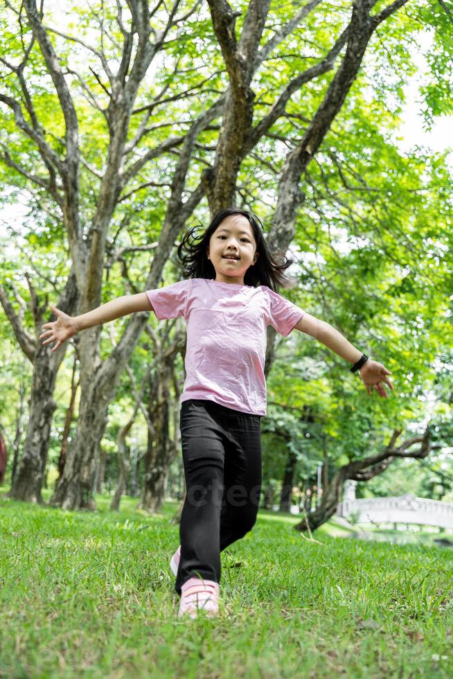 Portrait of child girl running and smiling in green park. photo