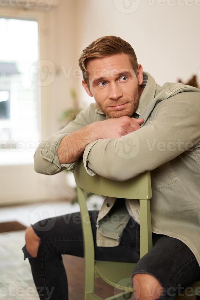 vertical retrato de hermoso masculino hombre, sentado en silla, mirando aparte, esperando para un orden en café tienda foto