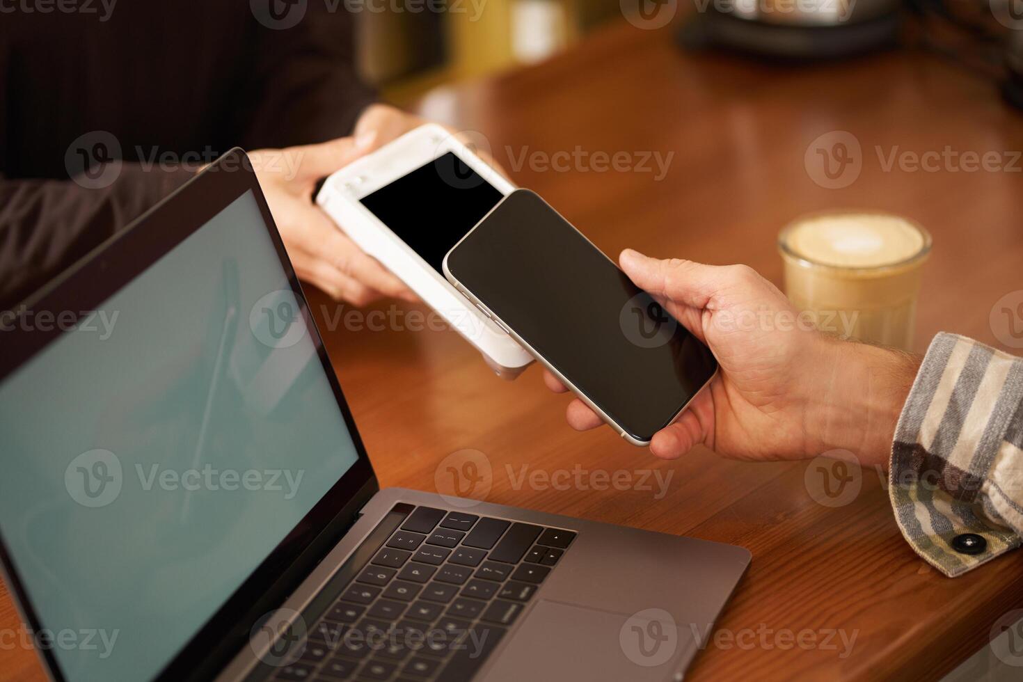 Cropped shot of hand pressing phone to POS paying terminal to pay contactless for an order, using smartphone to make purchase in cafe or co-working photo