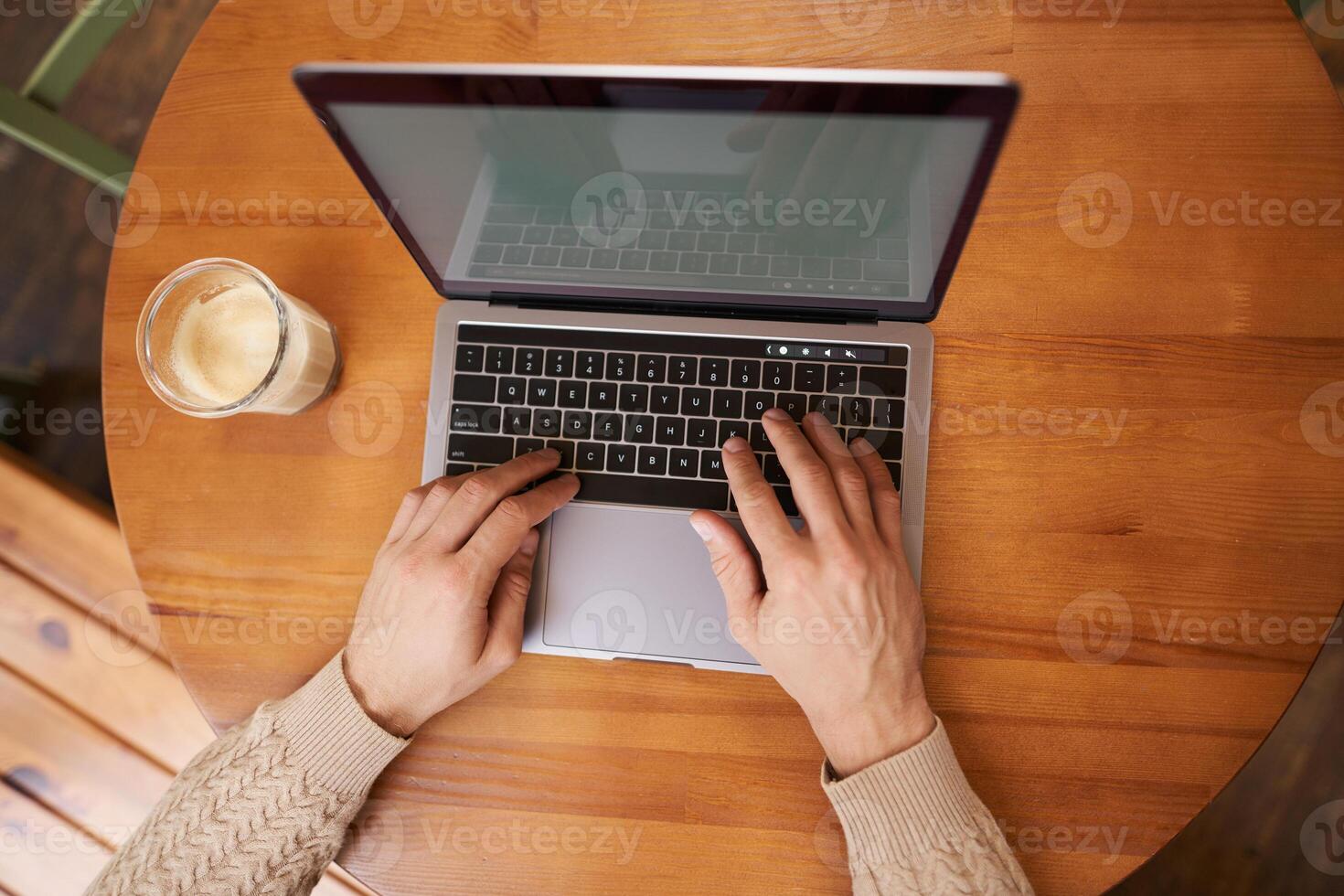 retrato de masculino manos, ordenador portátil y capuchino. hombre mecanografía en teclado, trabajando en café y Bebiendo café, cerca arriba de computadora pantalla y brazos foto