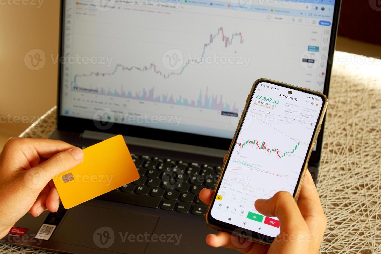 An investor who buys coins with a credit card. bitcoin chart on computer in background photo