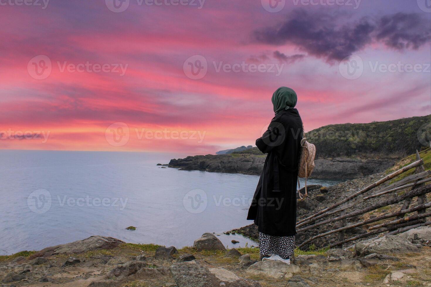 Lonely and sad girl watching sunset by the sea. Longing for the distance and the past. photo