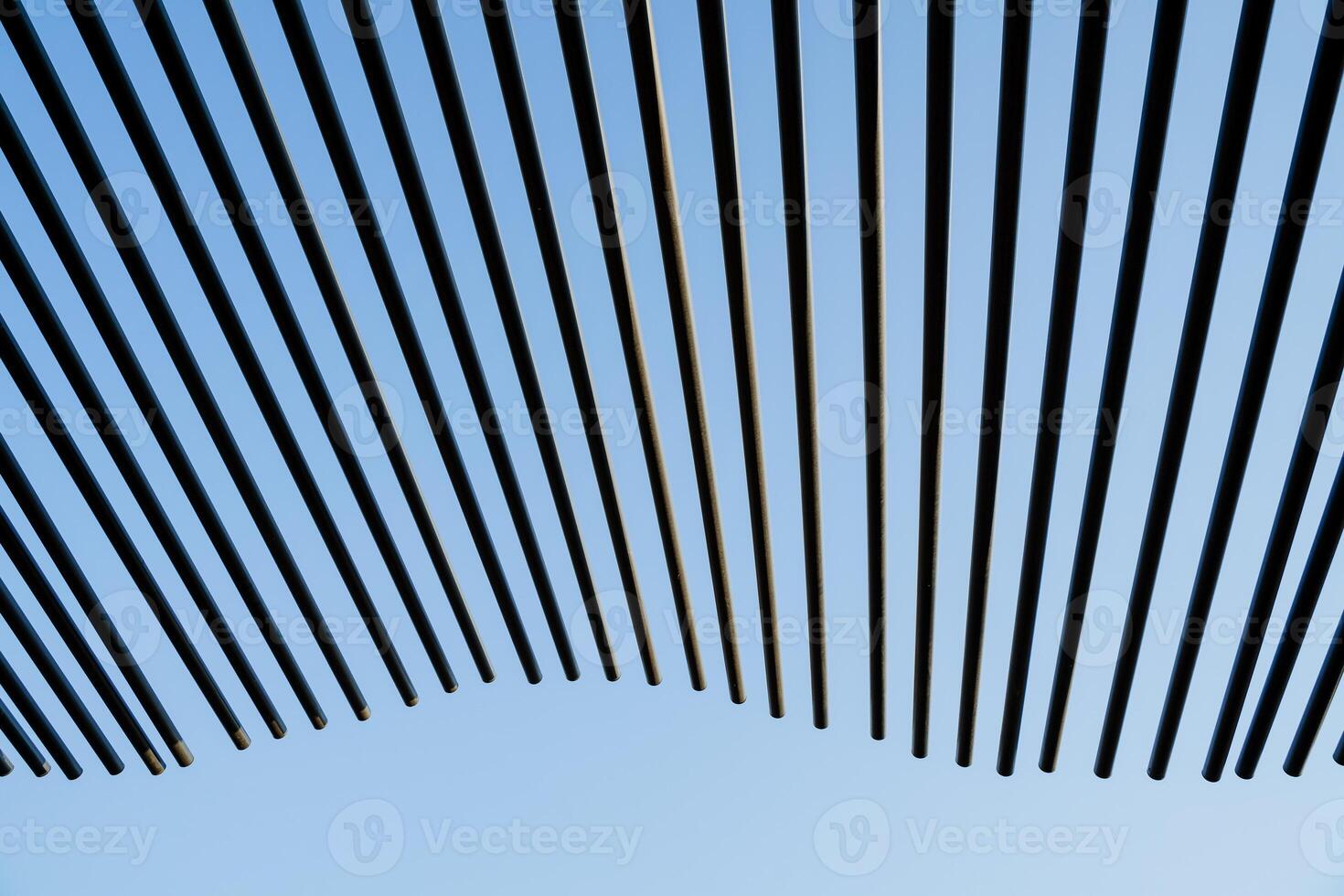 The pattern of the line of tubes sticking out into the sky, black wavy sticks against the background of the blue sky, the minimalistic design of the roof of the house, the abstract decoration photo