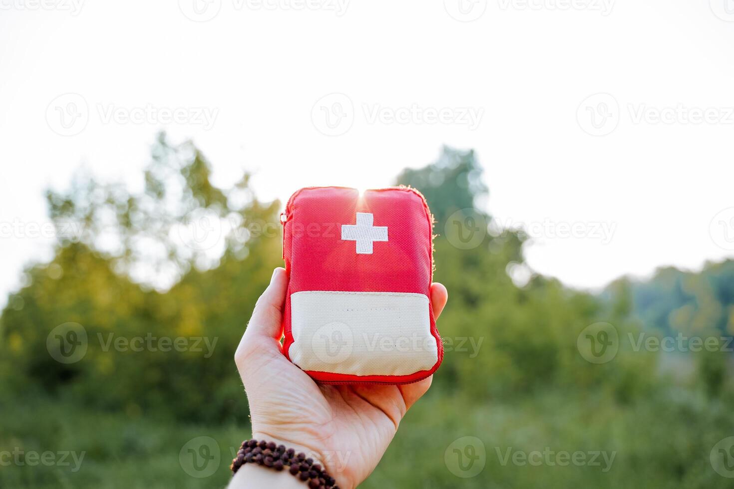 un rojo primero ayuda equipo en el rayos de el ajuste sol, destello de ligero brillar mediante un rojo bolsa, un primero ayuda equipo, medicamentos en un viaje bolsa. foto