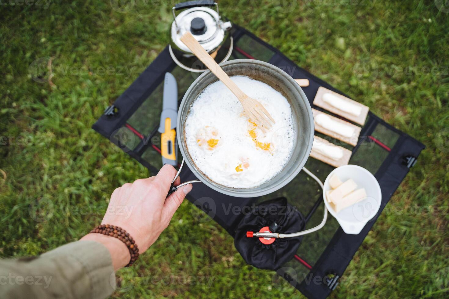 Scrambled eggs on a hike view from above, tourist kitchen in the campsite, a person cooks breakfast on a hike, fry eggs in a frying pan in nature, equipment for the field kitchen. photo