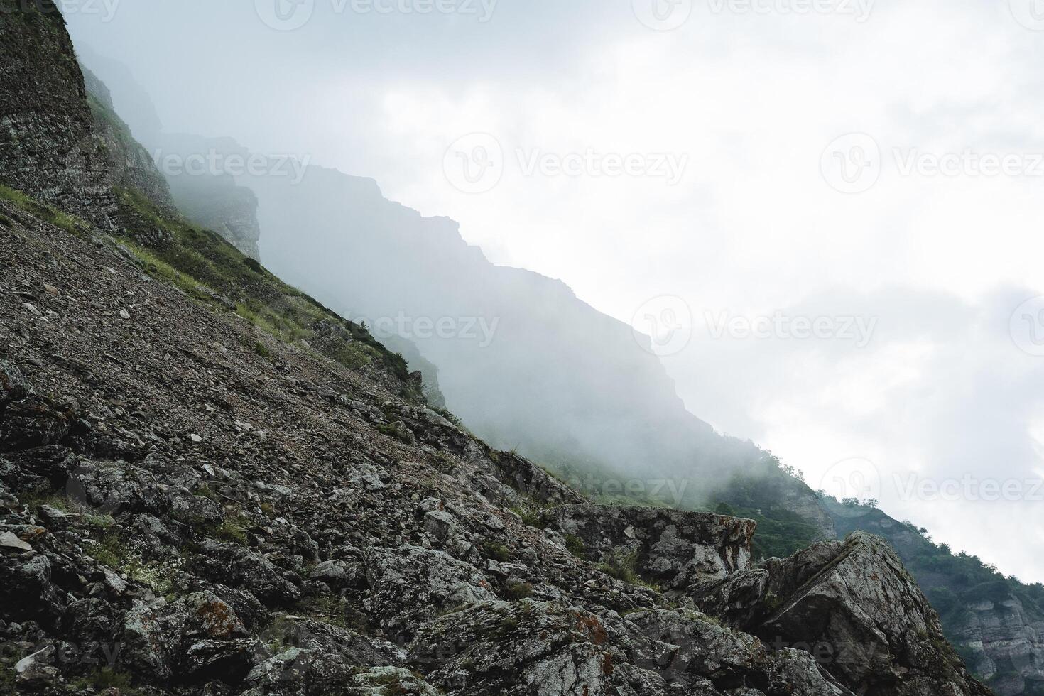 The rocky mountains of Dagestan fog fills the valley of the gorge, the landscape gloomy morning, stone scree from the mountain, cloudy weather. photo