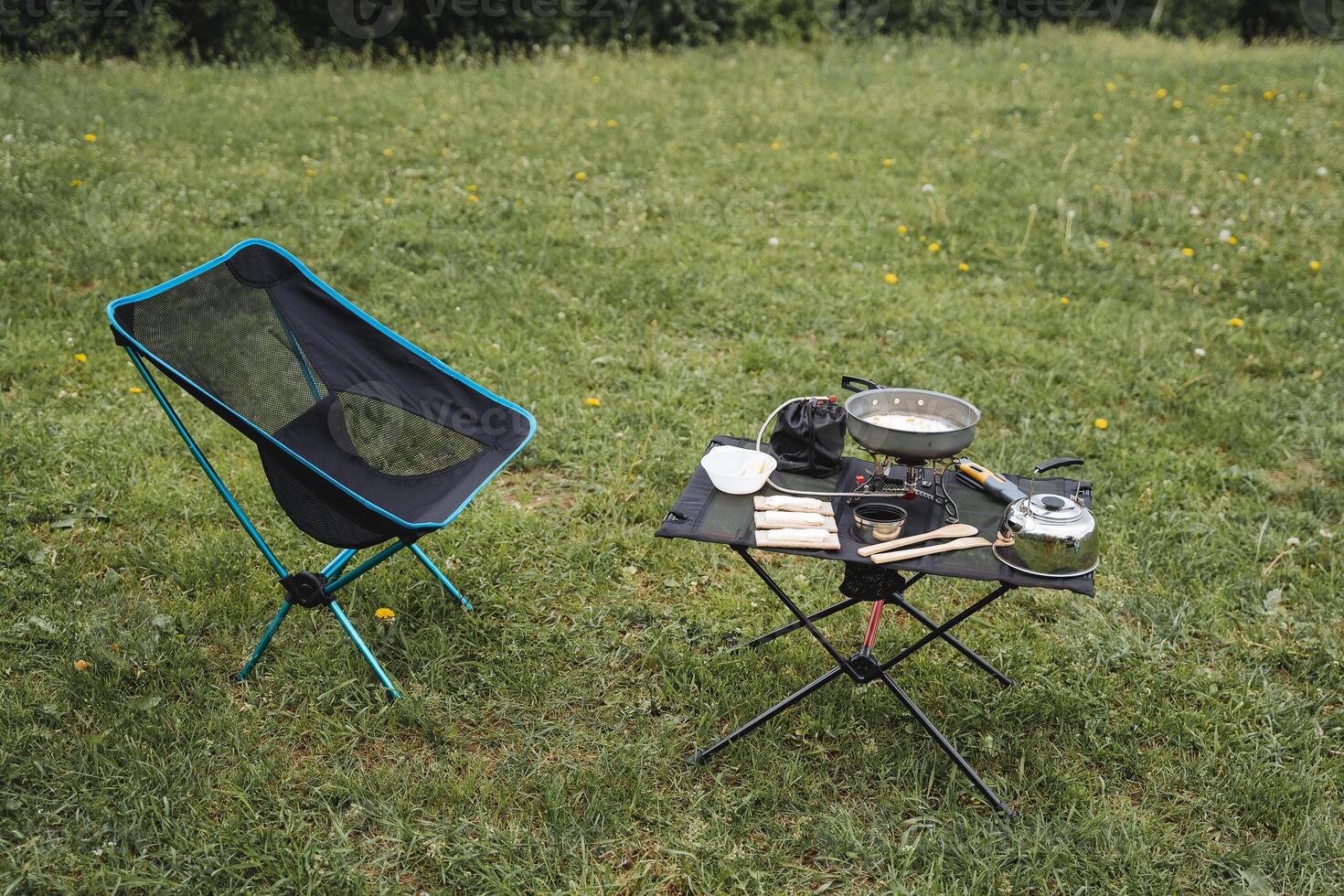 Camping furniture, folding chair and table, outdoor recreation, preparation of a camp kitchen, breakfast in the mountains, tourist dishes, equipment for trekking. photo