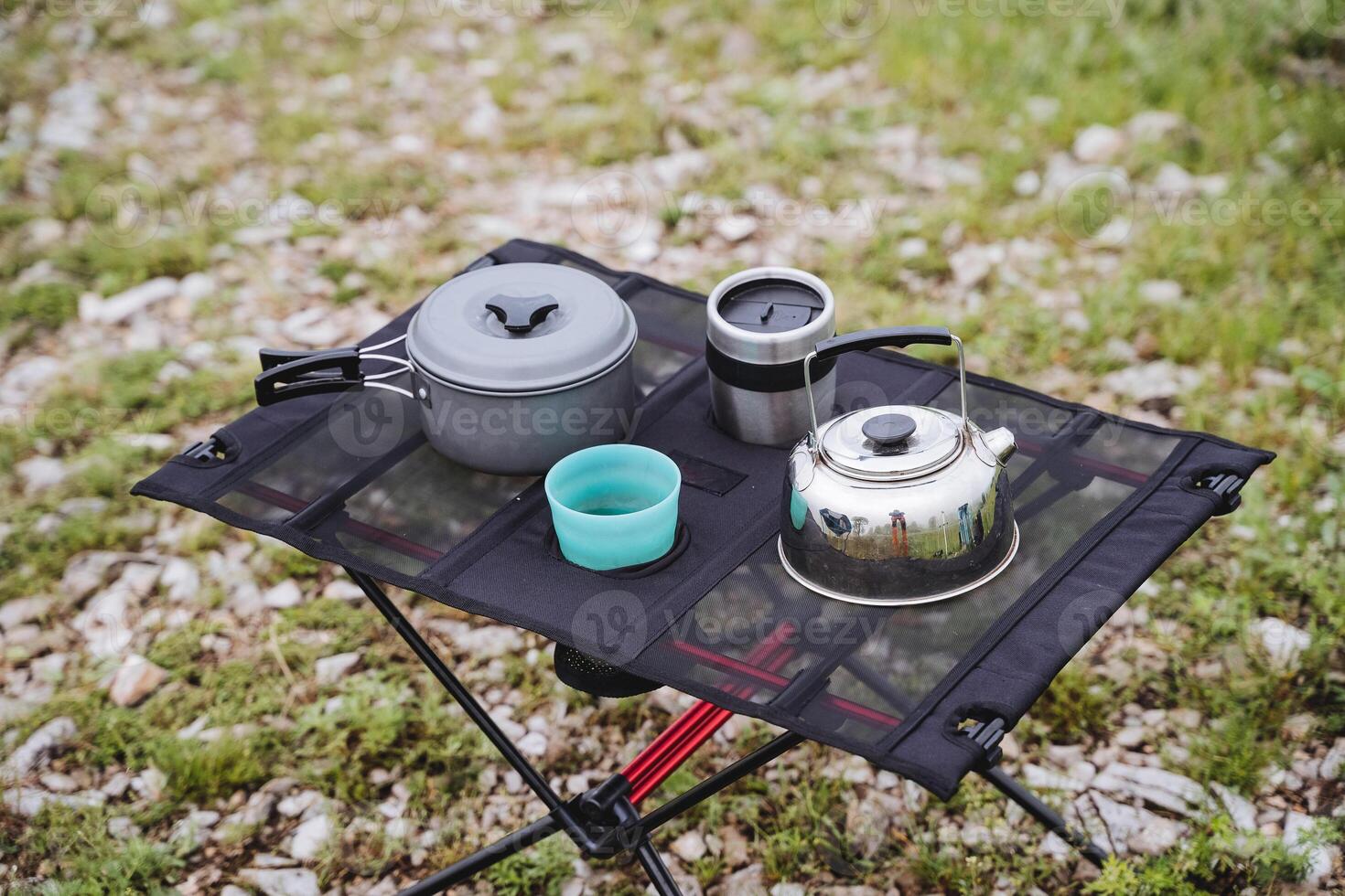 Tourist dishes for a hike are on the table, compact equipment is a small teapot made of metal, a pot for eating. photo