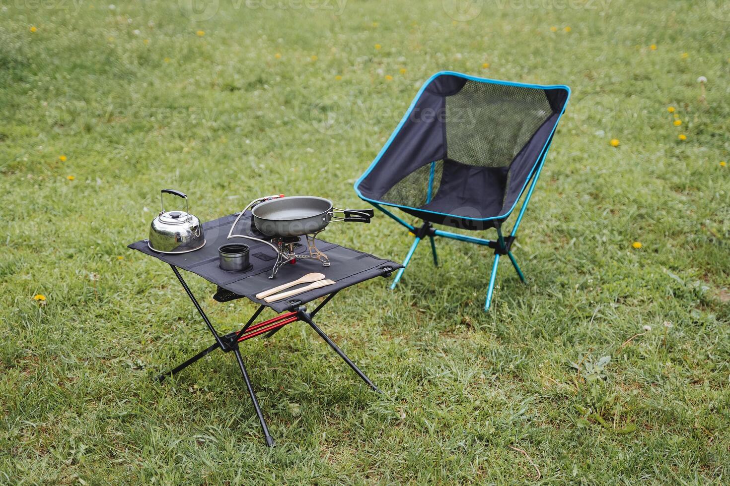 Camping furniture, compact equipment, camping equipment, camping utensils are on the table, a folding chair, a gas burner, a kettle. photo