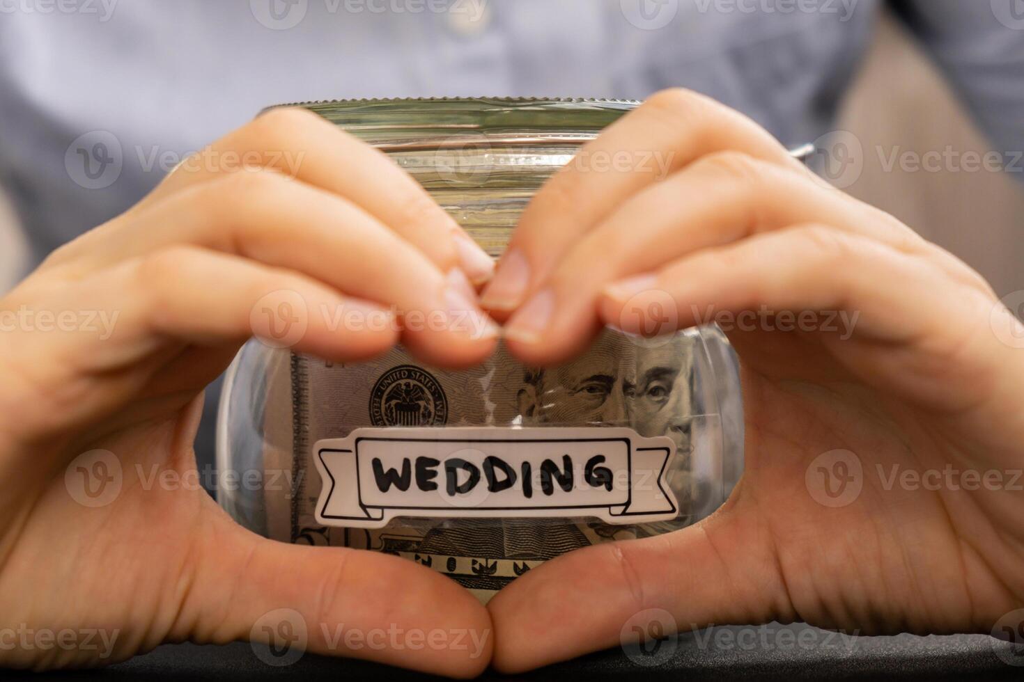 Unrecognizable woman showing heart sign Saving Money In Glass Jar filled with Dollars banknotes. WEEDING transcription in front of jar. Managing personal finances extra income for future insecurity background photo
