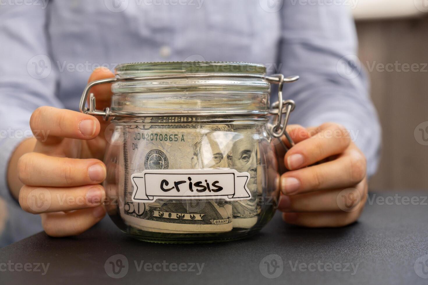 Female hands holding Glass jar full of American currency dollars cash banknote with text CRISIS. Preparation saving money. Moderate consumption and economy. Collecting money photo