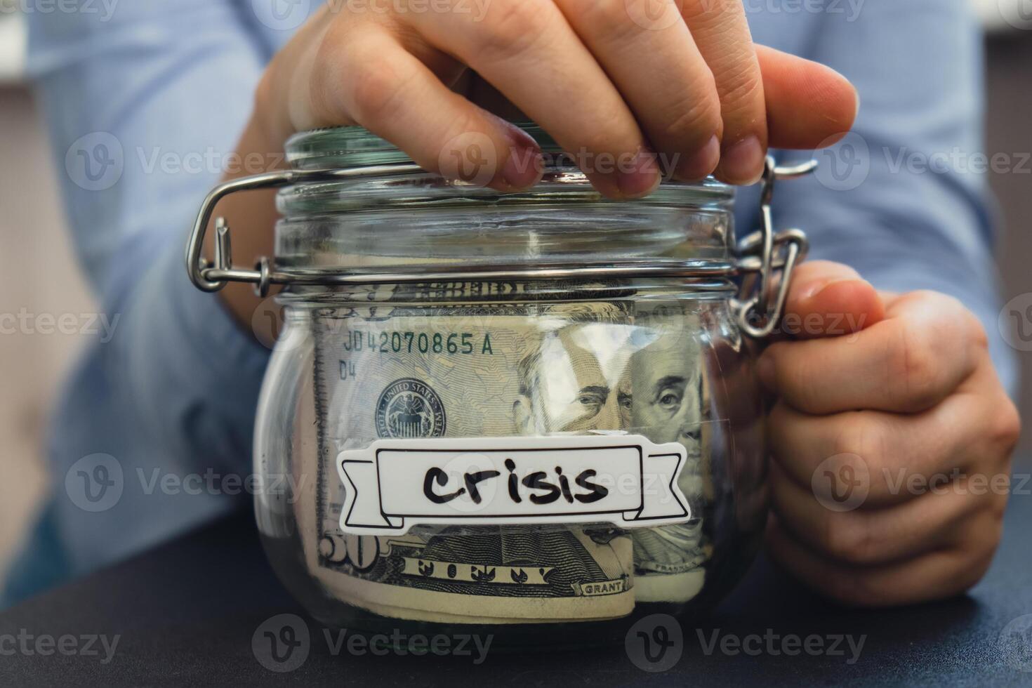 Unrecognizable woman holding Saving Money In Glass Jar filled with Dollars banknotes. CRISIS transcription in front of jar. Managing personal finances extra income for future insecurity background photo