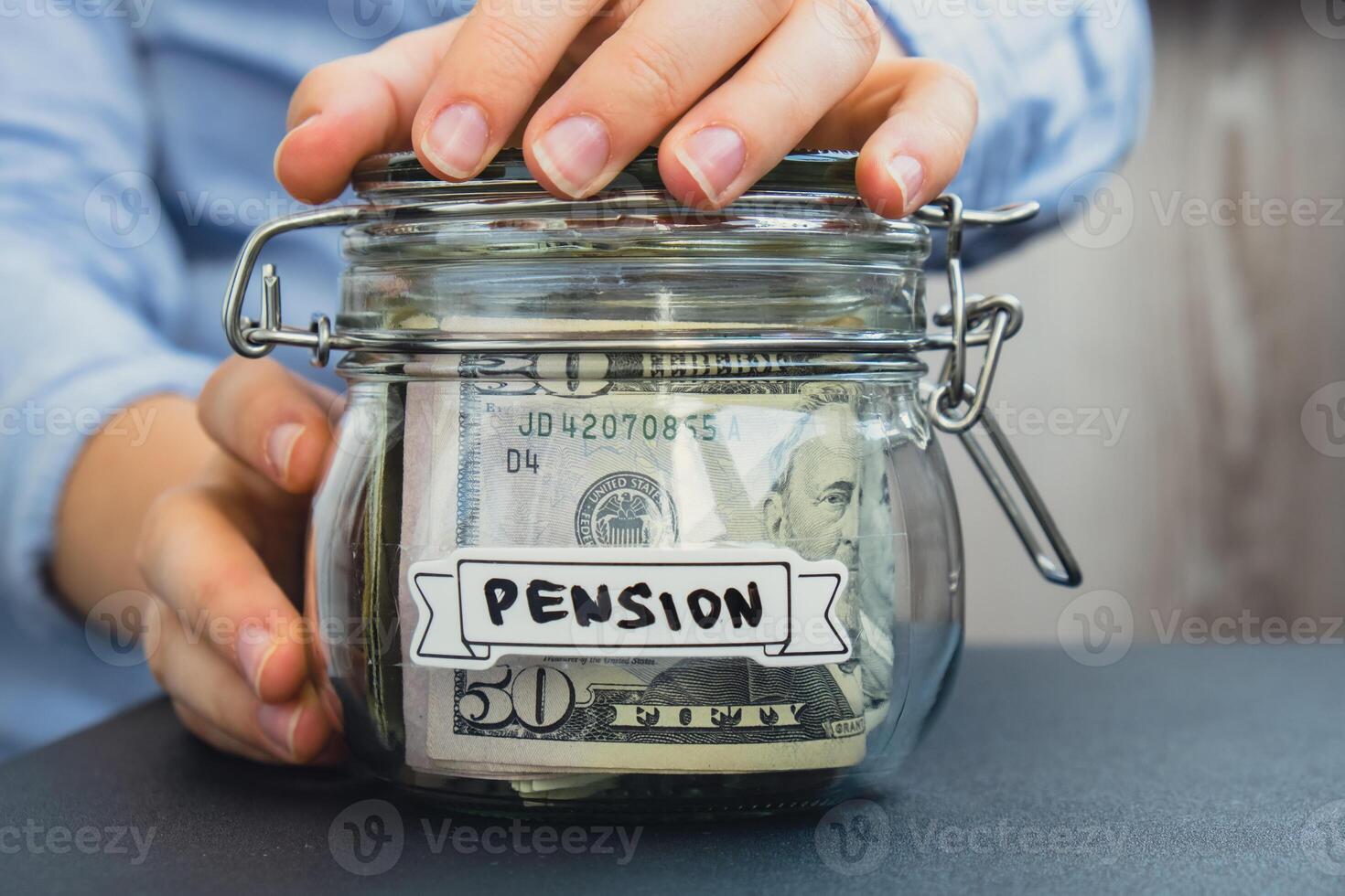 Female hands Saving Money In Glass Jar filled with Dollars banknotes. PENSION transcription in front of jar. Managing personal finances extra income for future insecurity background photo