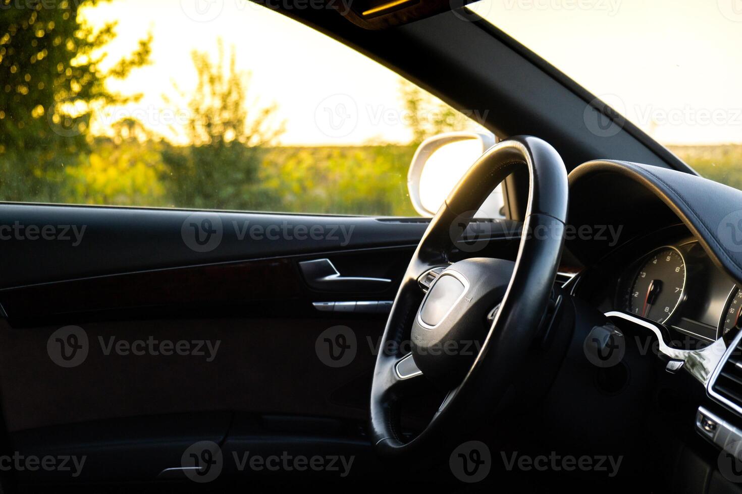 Steering wheel and Interior of modern luxury car during sunset on highway road. Details of multimedia menu control system panel, dashboard inside. Prestige sport automobile. Selective focus photo