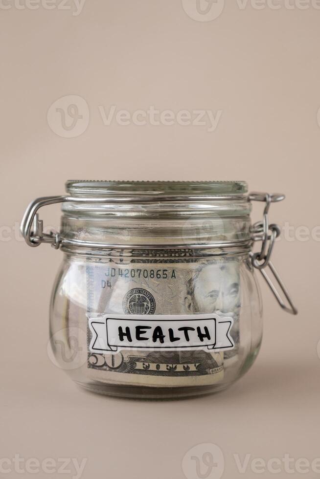 Glass jar full of American currency dollars cash banknote with text HEALTH. Preparation saving money. Moderate consumption and economy. Collecting money photo