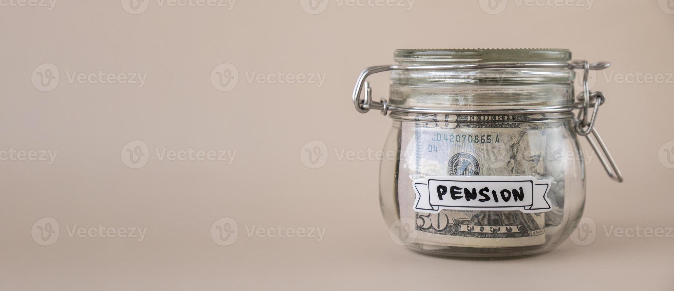 Saving Money In Glass Jar filled with Dollars banknotes. PENSION transcription in front of jar. Managing personal finances extra income for future insecurity. Beige background photo